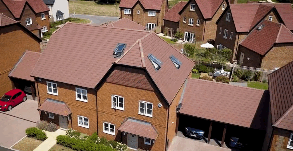 Aerial view of a residential brick home with pitched roof and surrounding houses.